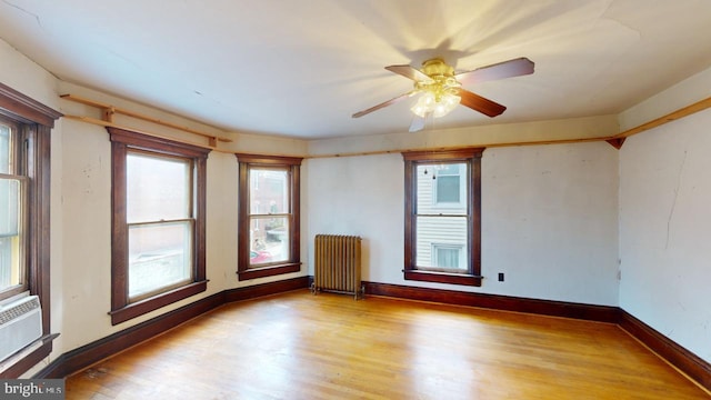 spare room with light hardwood / wood-style floors, radiator heating unit, and ceiling fan