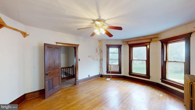 empty room with light wood-type flooring, radiator, ceiling fan, and baseboards