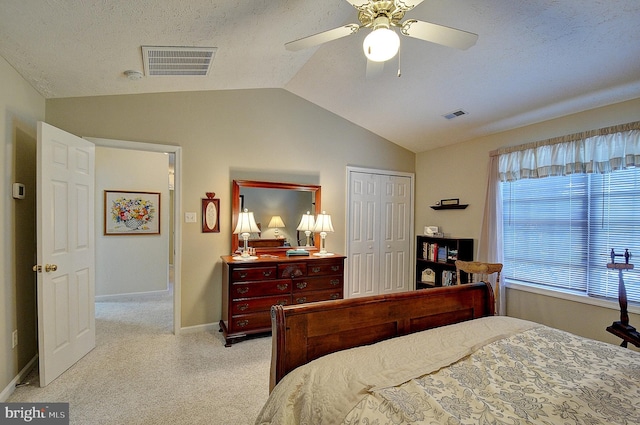 bedroom with a closet, a textured ceiling, lofted ceiling, ceiling fan, and light colored carpet