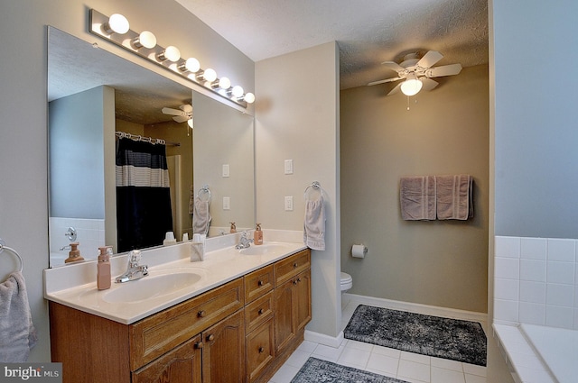 bathroom with vanity, a textured ceiling, tile patterned floors, tiled bath, and toilet