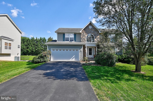 view of property featuring central AC unit, a garage, and a front lawn