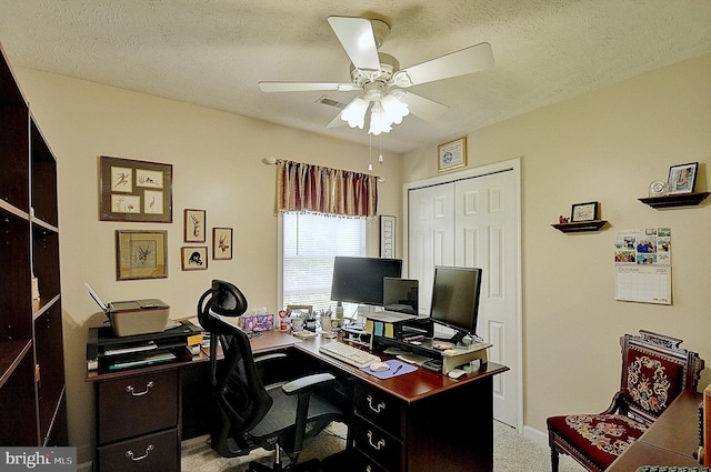 carpeted office space with a textured ceiling and ceiling fan