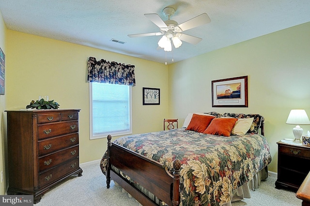 carpeted bedroom featuring ceiling fan and a textured ceiling