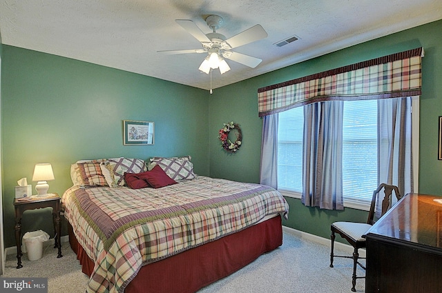 bedroom with a textured ceiling, light carpet, and ceiling fan