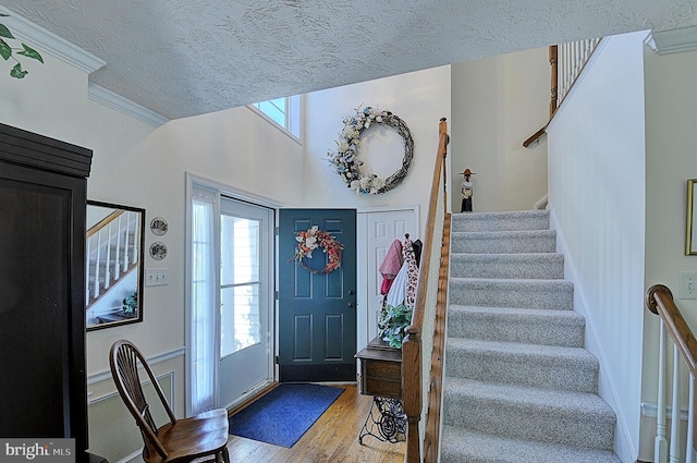 foyer with ornamental molding, wood-type flooring, and a textured ceiling