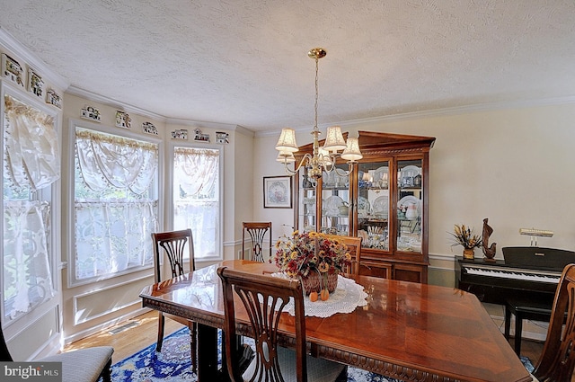 dining space with an inviting chandelier, wood-type flooring, a textured ceiling, and crown molding