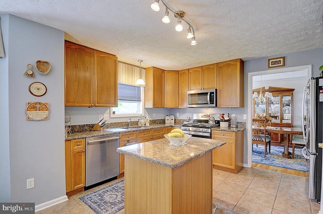 kitchen featuring appliances with stainless steel finishes, light stone countertops, a center island, and decorative light fixtures