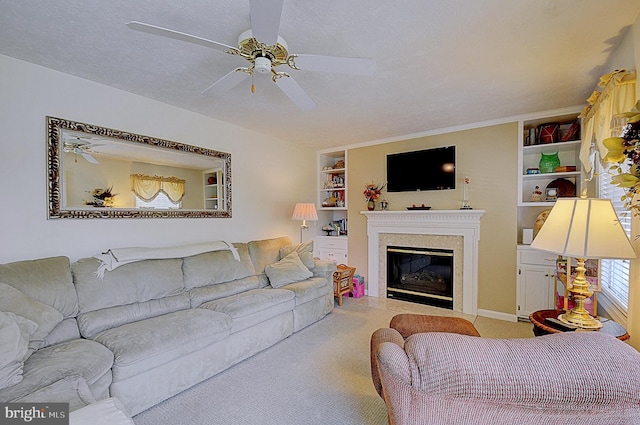 living room featuring built in shelves, ceiling fan, carpet floors, and a textured ceiling