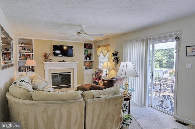 carpeted living room featuring built in shelves, ceiling fan, and a textured ceiling