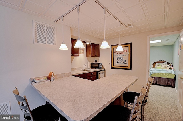 kitchen featuring a breakfast bar, sink, kitchen peninsula, carpet floors, and hanging light fixtures