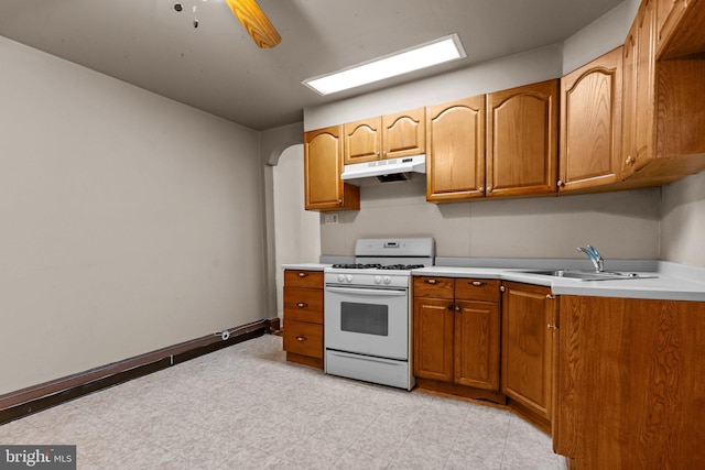 kitchen featuring ceiling fan, white range with gas stovetop, and sink