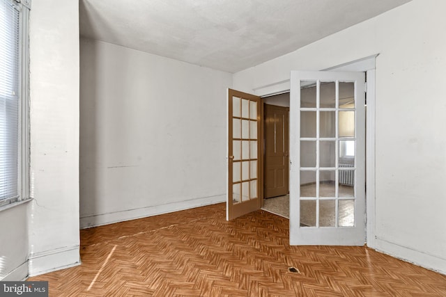 empty room featuring radiator, light parquet flooring, and french doors