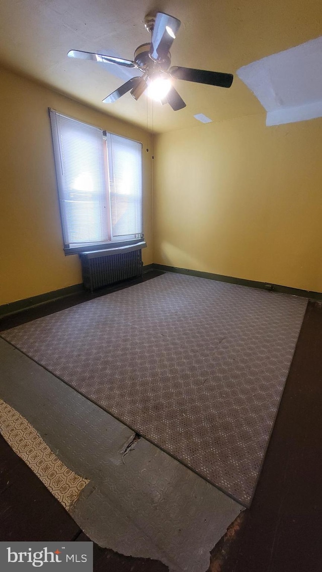 spare room featuring radiator, carpet flooring, and ceiling fan