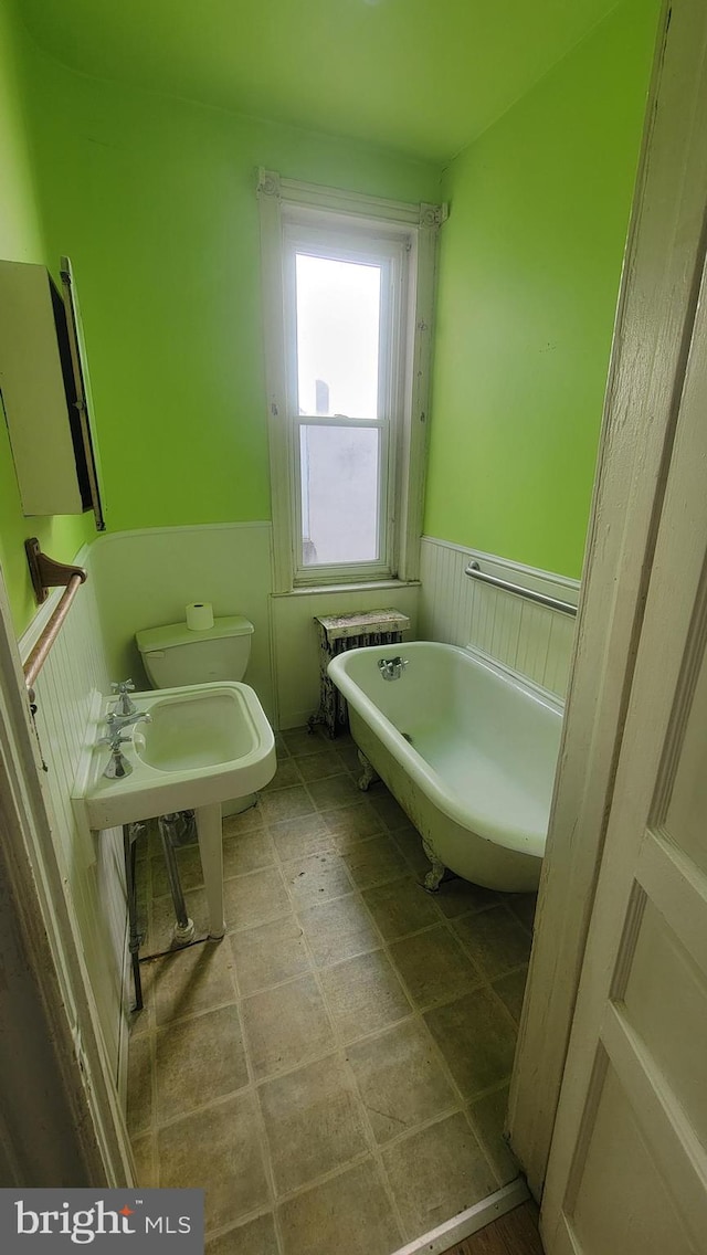 bathroom with toilet, radiator heating unit, and a tub