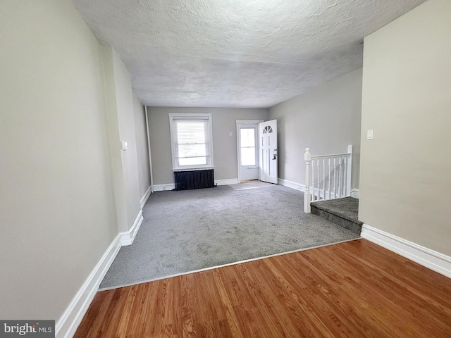 interior space with a textured ceiling, wood-type flooring, and radiator