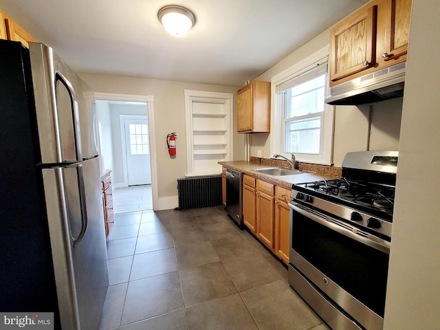 kitchen featuring dark tile patterned floors, radiator, appliances with stainless steel finishes, and sink