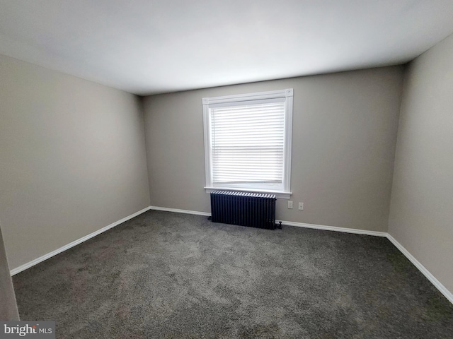 empty room featuring radiator heating unit and dark carpet