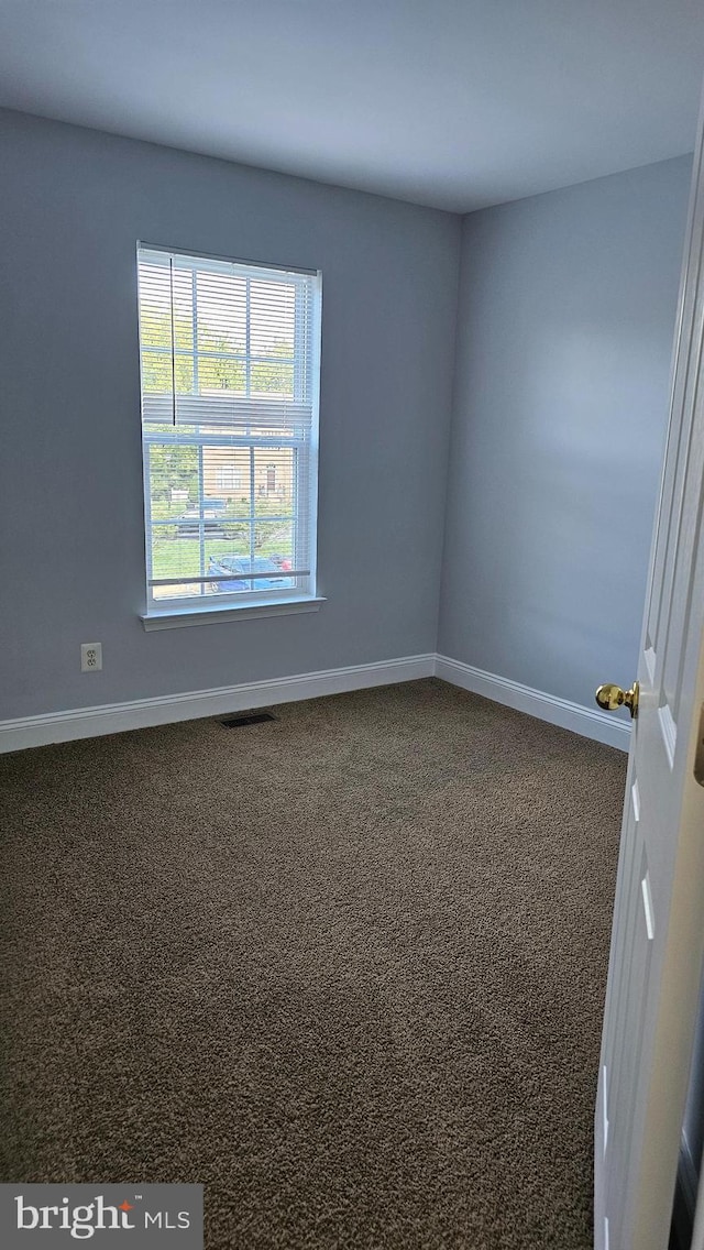 spare room with dark carpet