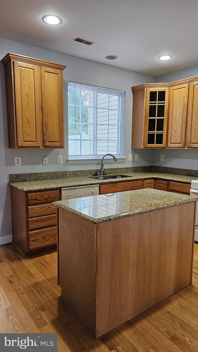 kitchen with light hardwood / wood-style flooring, sink, dishwashing machine, and a kitchen island