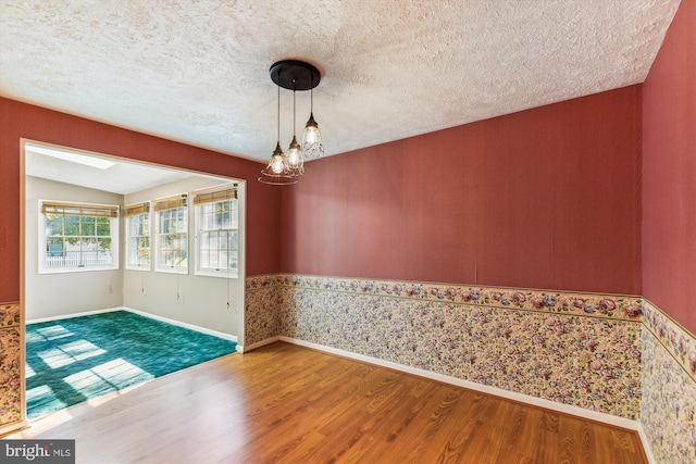 empty room with a textured ceiling, vaulted ceiling, and hardwood / wood-style floors