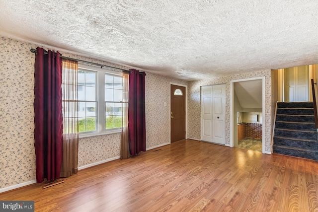 unfurnished living room featuring a textured ceiling and wood-type flooring