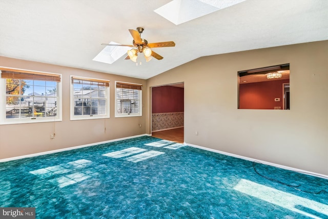 carpeted spare room featuring lofted ceiling with skylight and ceiling fan