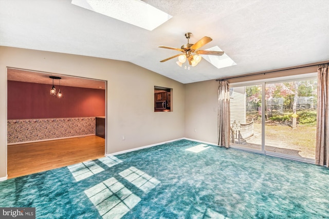 empty room with vaulted ceiling with skylight, a textured ceiling, wood-type flooring, and ceiling fan