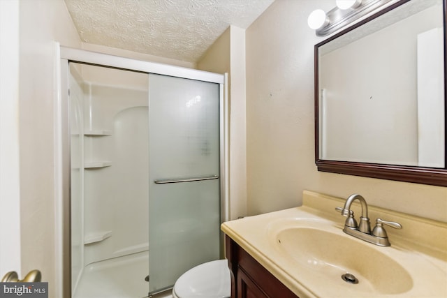 bathroom featuring vanity, toilet, a textured ceiling, and a shower with shower door