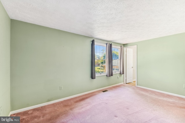 unfurnished room with light carpet and a textured ceiling