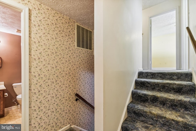 staircase with a textured ceiling