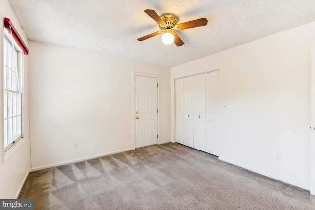 spare room with a textured ceiling, light colored carpet, plenty of natural light, and ceiling fan