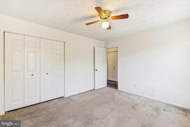 unfurnished bedroom with light carpet, a textured ceiling, a closet, and ceiling fan