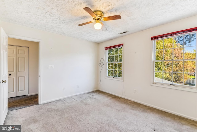 carpeted empty room featuring ceiling fan and a textured ceiling