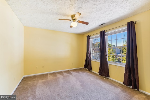 spare room with ceiling fan, a textured ceiling, and light colored carpet