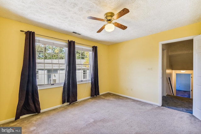 carpeted spare room with ceiling fan and a textured ceiling