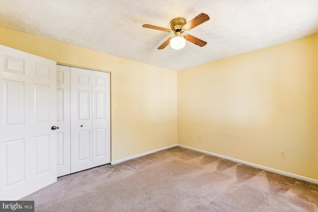 unfurnished bedroom featuring a closet, ceiling fan, a textured ceiling, and carpet floors