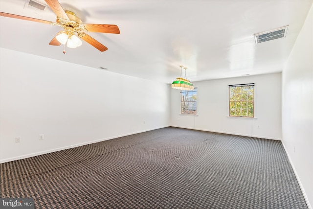 spare room featuring dark colored carpet and ceiling fan