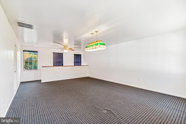 unfurnished room with dark carpet and ceiling fan