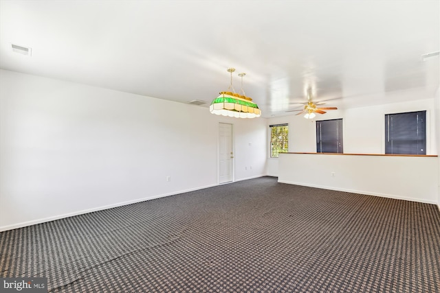 unfurnished room with ceiling fan and dark carpet