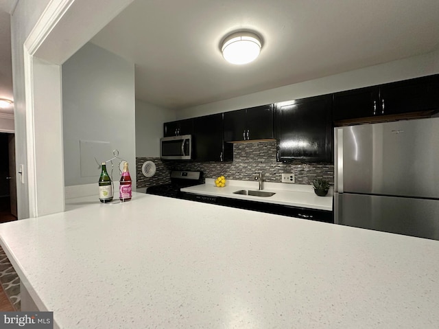 kitchen featuring sink, kitchen peninsula, stainless steel appliances, and tasteful backsplash