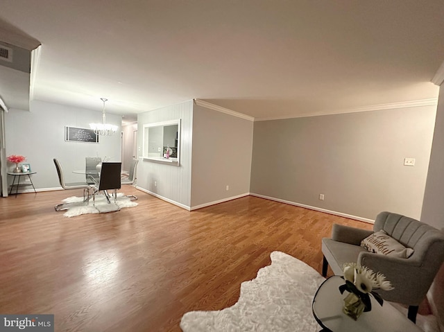 sitting room with crown molding, hardwood / wood-style flooring, and a chandelier