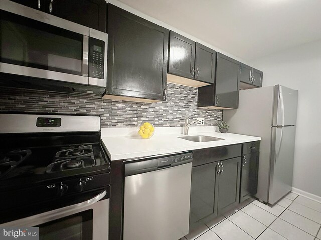 kitchen featuring backsplash, appliances with stainless steel finishes, sink, and light tile patterned floors