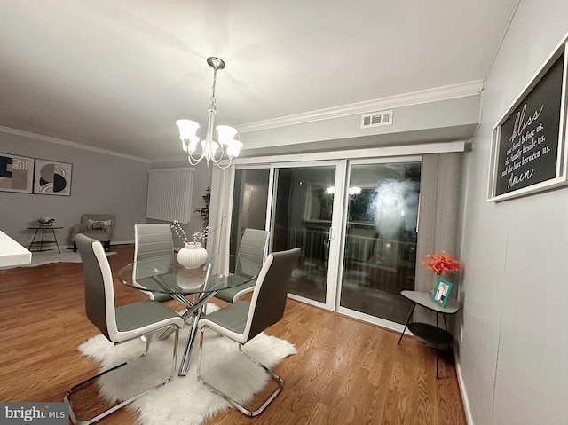 dining space with crown molding, a notable chandelier, and wood-type flooring