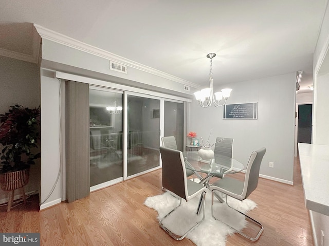 dining room with light hardwood / wood-style floors, crown molding, and a chandelier