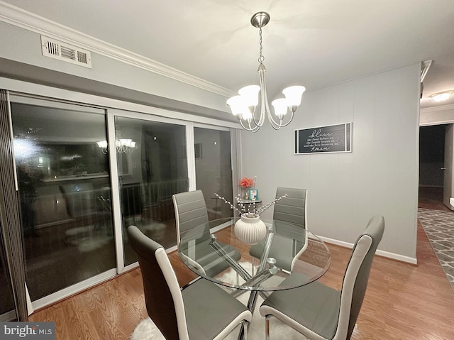 dining room with light hardwood / wood-style floors, crown molding, and a notable chandelier