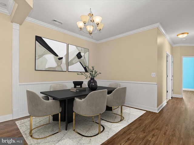 dining space featuring crown molding, ornate columns, wood-type flooring, and an inviting chandelier