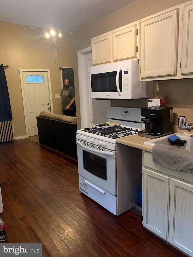 kitchen with white appliances, white cabinetry, and dark hardwood / wood-style flooring