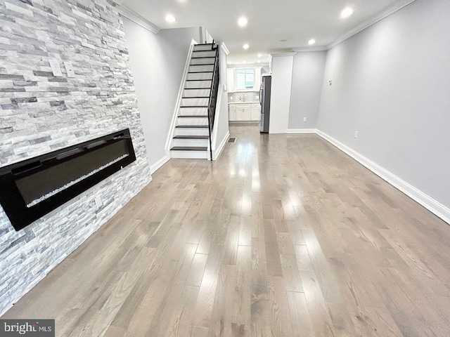 unfurnished living room featuring light wood-type flooring, crown molding, and a fireplace