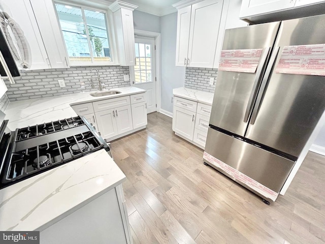 kitchen featuring white cabinetry, light stone countertops, sink, and stainless steel fridge