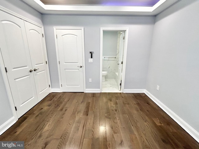 unfurnished bedroom with dark wood-type flooring and ensuite bathroom